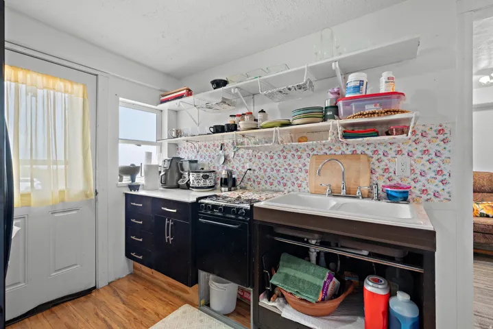 Compact kitchen featuring wood-finish flooring, white walls, and a white door with a window