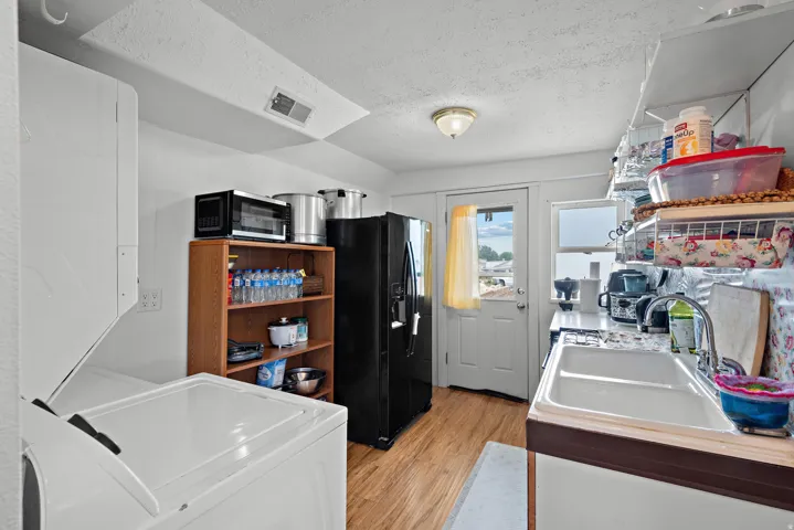 Kitchen space featuring wood-finish flooring, a white porcelain sink, and white upper shelving