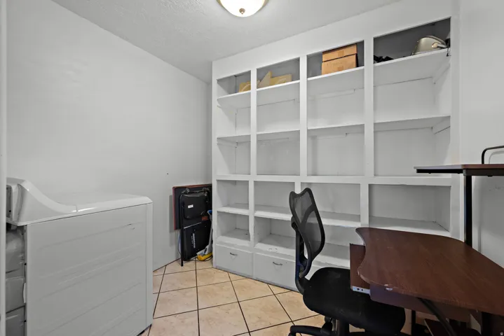 Spacious room featuring extensive built-in shelving, tile flooring, and a ceiling-mounted light fixture