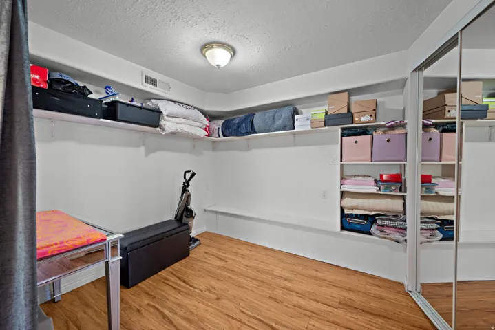 Spacious room featuring wood-finish flooring, built-in shelving, a built-in storage bench, and mirrored closet doors