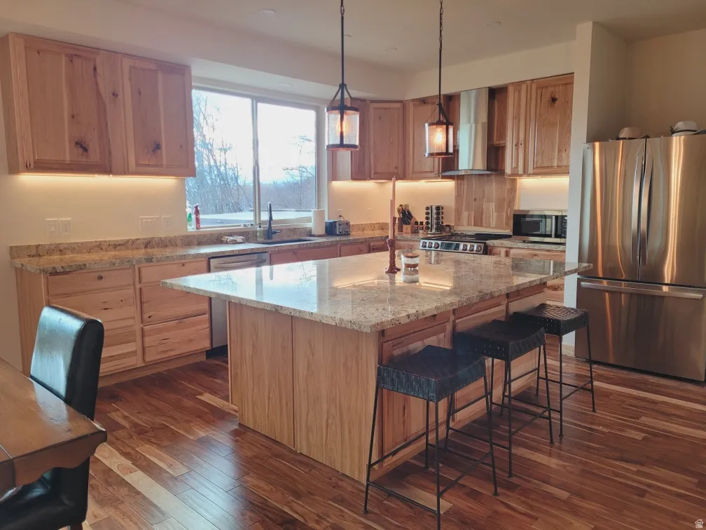 Kitchen featuring wood cabinetry, granite countertops, stainless steel appliances, and wood-finish flooring