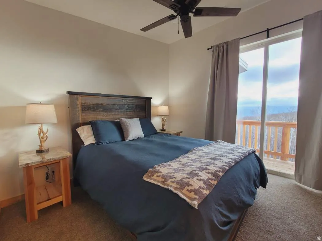 Bedroom featuring a distressed wood-finish headboard, a ceiling fan, and carpeted flooring