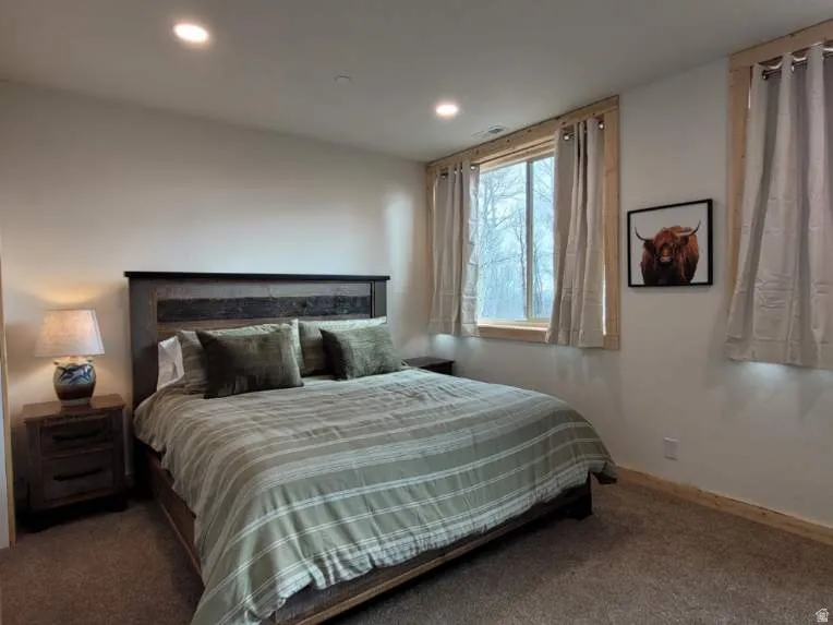Bedroom featuring recessed lighting, a window with natural wood trim, and carpeting