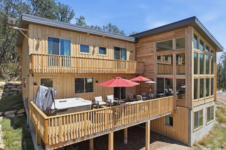 Multi-level wood-sided property featuring extensive decking, a hot tub, and multiple sliding glass doors