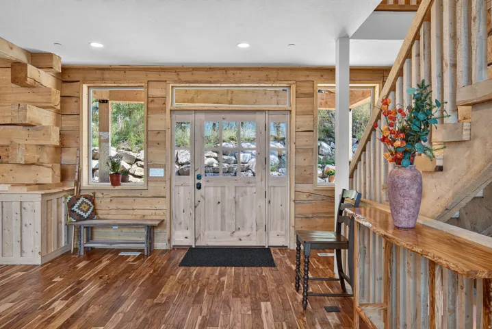 Wood-finish flooring throughout, complemented by wood-paneled walls and a wood staircase with a natural wood railing