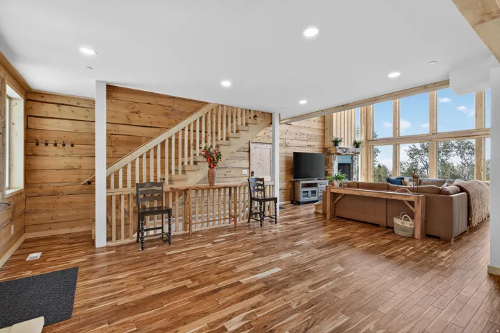 Spacious interior featuring wood-finish flooring, wood plank walls, and a prominent staircase with wood balusters
