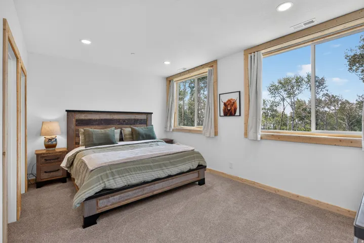 Carpeted bedroom featuring white walls, recessed lighting, and natural wood window trim