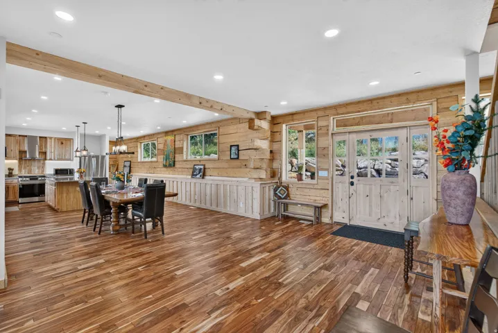 Expansive open-concept living space featuring wood-finish flooring and exposed wood beam accents