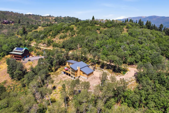 Contemporary residence featuring a light wood-tone exterior, dark gray roof, and multiple exterior decks
