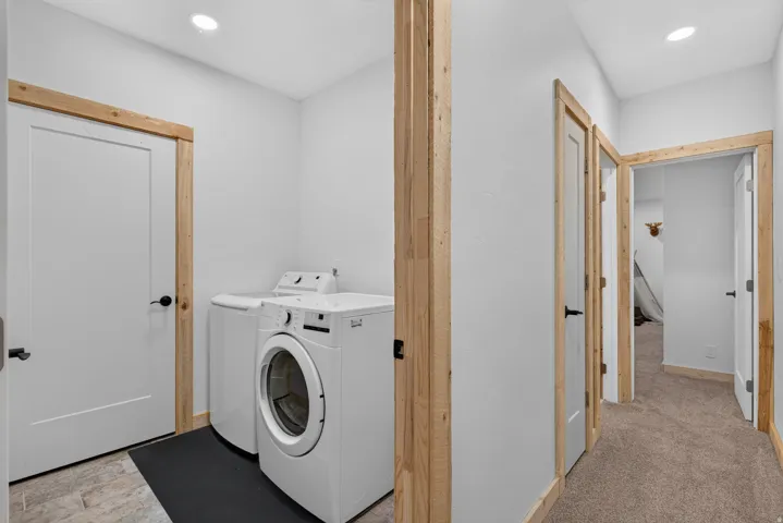 Dedicated laundry area featuring a front-loading washing machine, a top-loading washing machine, recessed lighting, and white walls