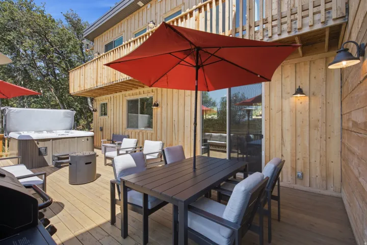 Expansive wood deck with a built-in hot tub, outdoor dining area, and board-and-batten siding
