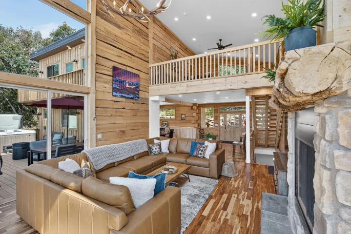 Spacious living area featuring double-height ceilings, a stone fireplace, and wood-finish flooring