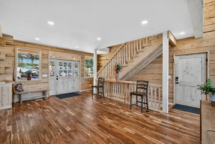 Entry foyer featuring wide plank wood-finish flooring, natural wood paneling, and a double-door entry with transom and sidelight windows