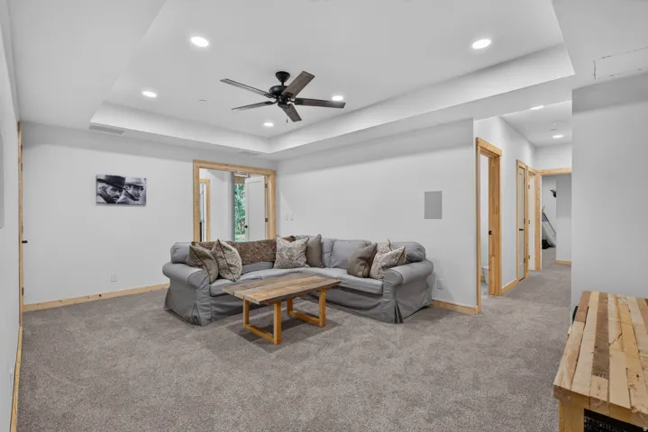 Spacious living area featuring a tray ceiling with recessed lighting and a ceiling fan