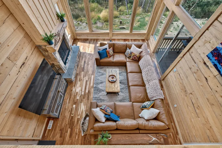 Spacious living area featuring high ceilings with exposed wood beams, extensive natural wood wall paneling, and wood-finish flooring