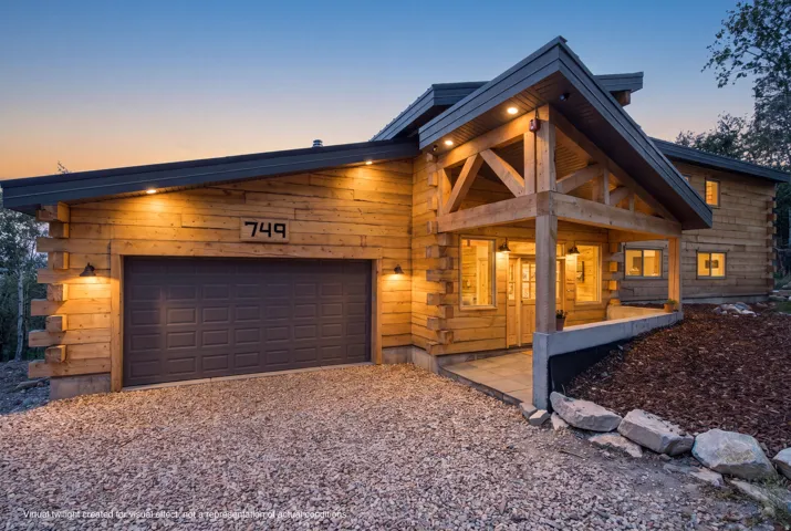 Crafted log home exterior with a covered entry, gravel driveway, and an attached garage