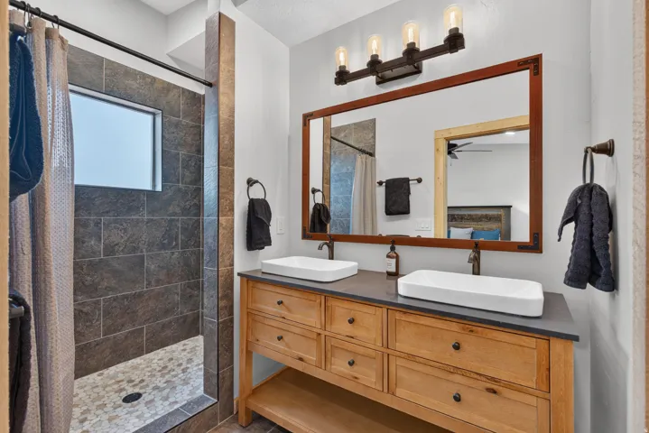 Spa-inspired primary bathroom featuring dual vessel sinks, custom wood cabinetry with ample storage, and a quartz countertop