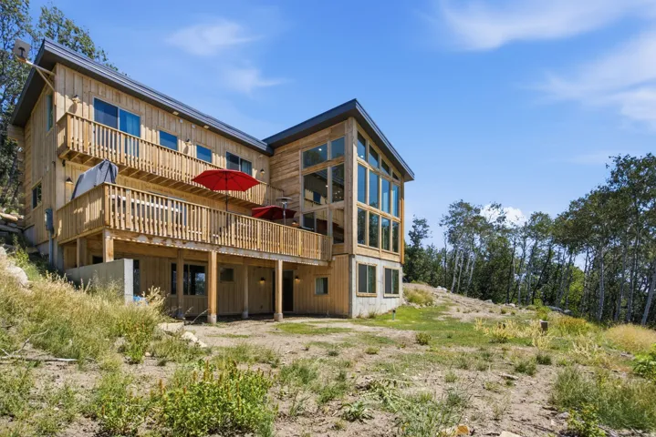 Contemporary timber-clad residence featuring a multi-level deck, expansive windows, a prominent gable roofline, and a walk-out lower level