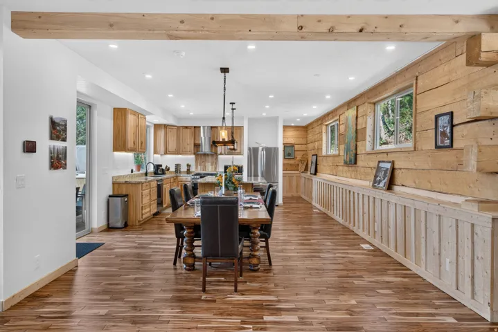 Open-concept living space featuring wood-finish flooring, exposed wood beam, recessed lighting, and a full kitchen with light wood cabinetry and granite countertops