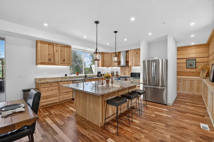 Gourmet kitchen featuring a large central island with seating, natural wood cabinetry, granite countertops, and stainless steel appliances