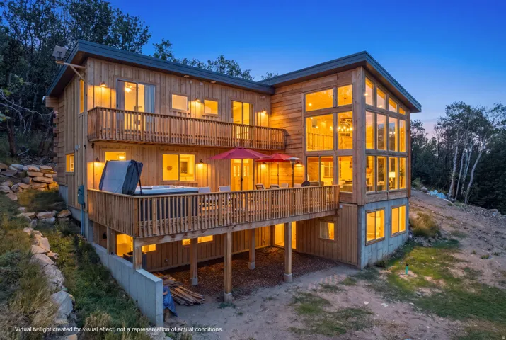 Multi-level wood-sided residence featuring extensive decking, a hot tub, and a two-story window wall