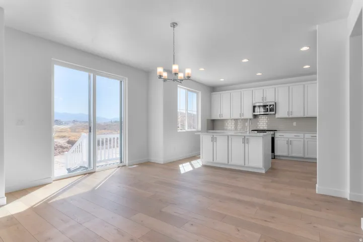 Spacious open-concept living area featuring wood-finish flooring, a contemporary chandelier, and recessed lighting