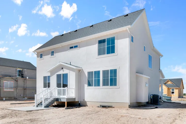Stucco exterior with multiple windows, a white deck and railings, and a concrete patio