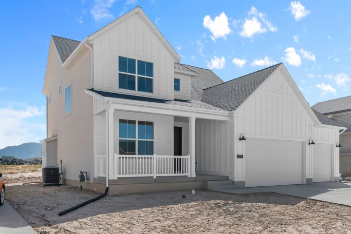 Modern farmhouse exterior with white vertical siding, a covered front porch, and a two-car garage