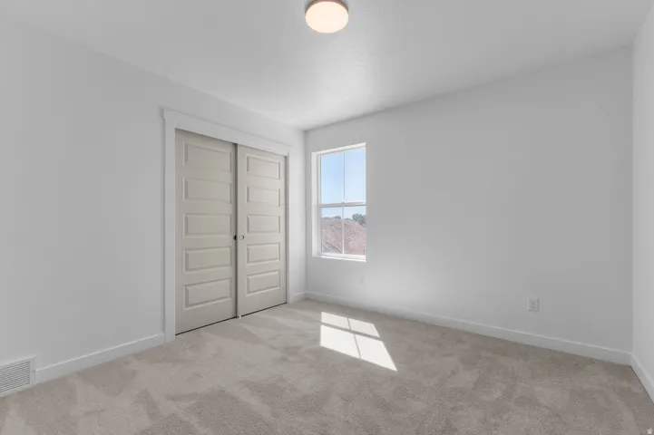 Neutral toned carpeted flooring, white painted walls, and a ceiling-mounted light fixture