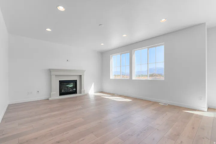 Recessed lighting, light wood-finish flooring, and a fireplace with a mantel