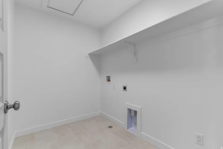 Laundry room with tile flooring, wall-mounted shelving, and utility hookups