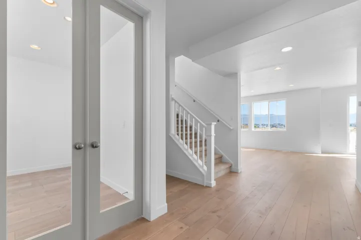 Light wood-finish flooring throughout, recessed lighting, and a white staircase with carpeted treads