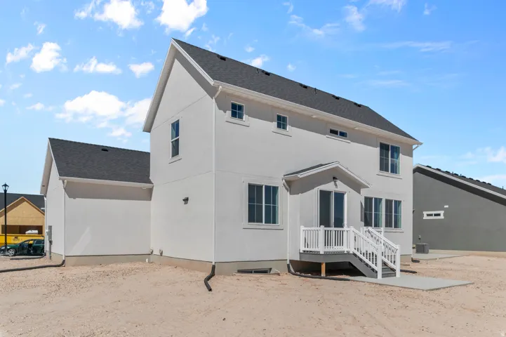 Stucco exterior with multiple windows, a concrete patio, and a deck with white railings