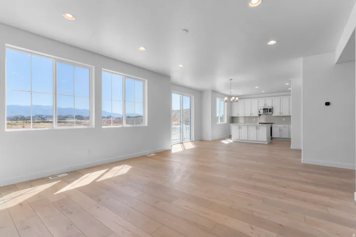 Expansive living space with wood-finish flooring, recessed lighting, and large windows