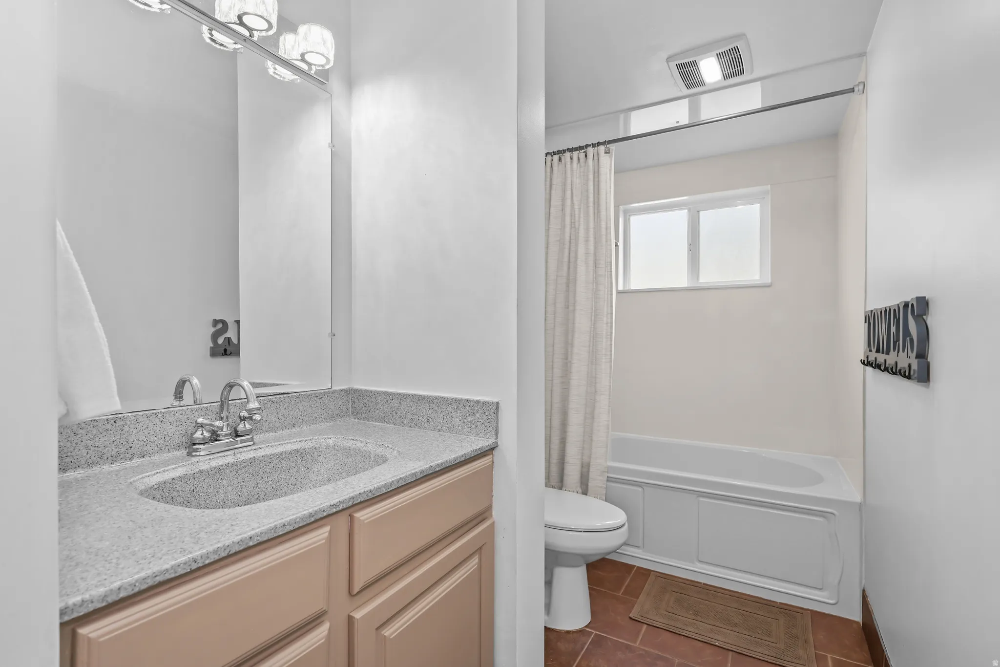 Bathroom featuring a single vanity with a light-toned countertop, a chrome faucet, and a wall-mounted mirror