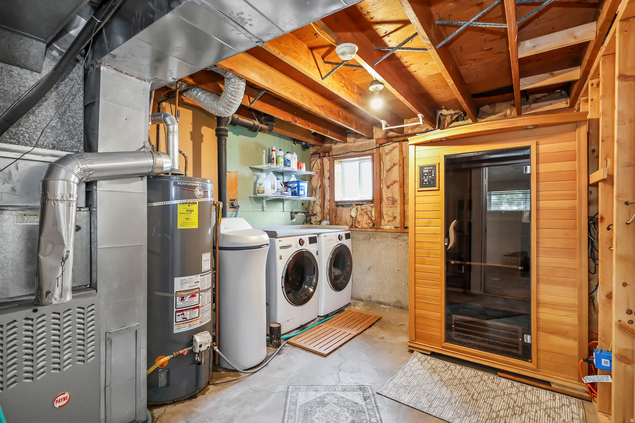 Dedicated laundry area featuring a front-loading washer and dryer, water softener, water heater, and furnace