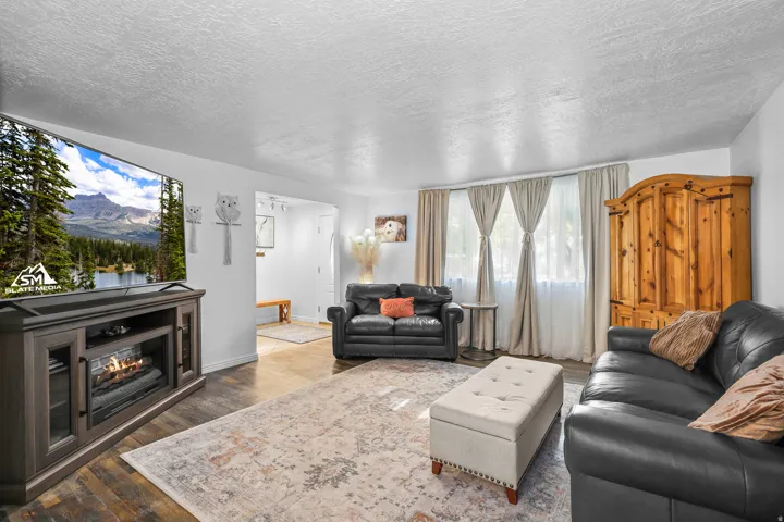Spacious living area featuring wood-finish flooring, a built-in media console with an electric fireplace insert, and multiple windows