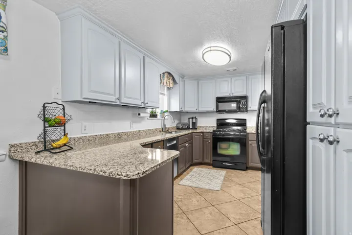 Kitchen featuring light-colored upper cabinetry, dark base cabinetry, and speckled countertops