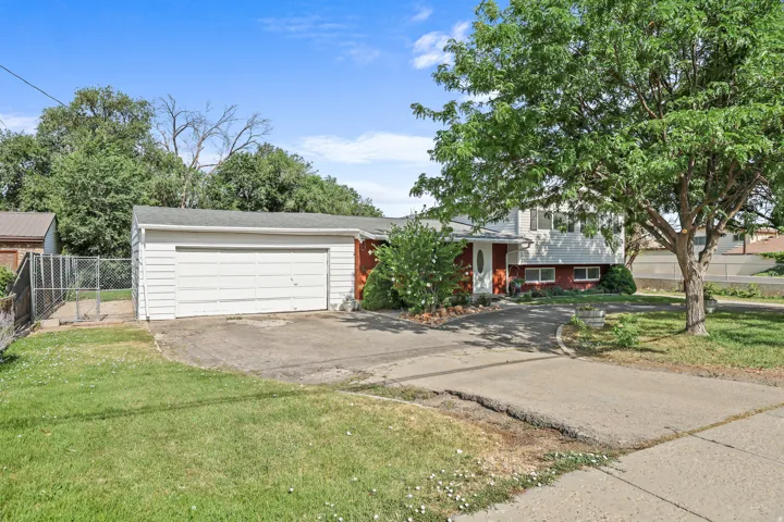 Split-level residence featuring a white and red exterior, an attached two-car garage with a white door, and a paved driveway