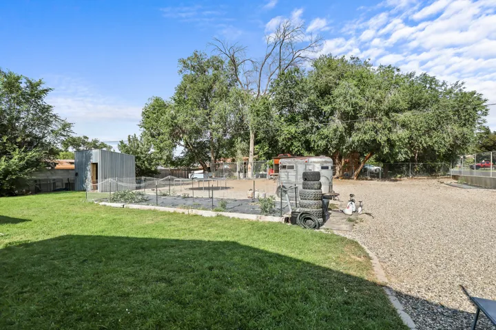 Expansive yard featuring a gravel area, manicured lawn, and mature trees
