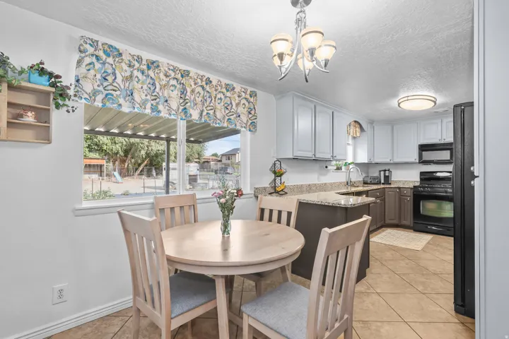 Kitchen featuring granite countertops, two-tone cabinetry, black appliances, and tile flooring