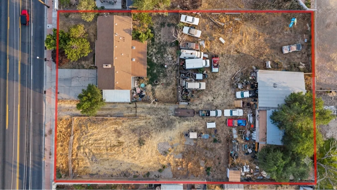 Aerial property overview featuring two distinct structures, a main residence with a brown shingle roof, and an additional auxiliary building with a metal roof