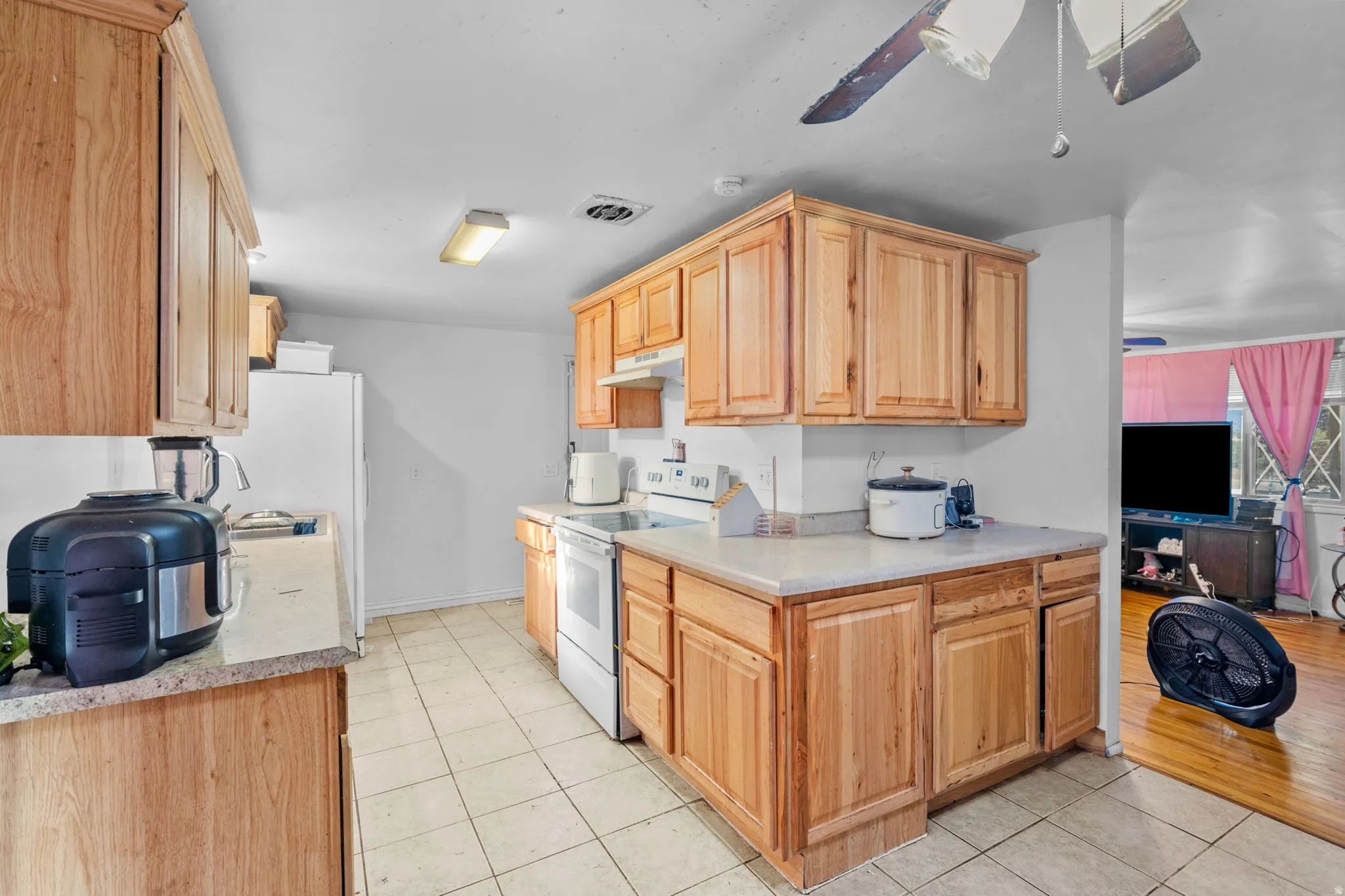 Kitchen featuring wood cabinetry, white appliances, and tiled flooring