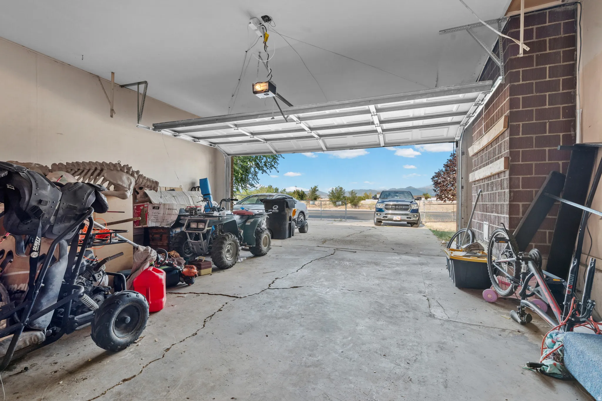 Attached garage with an overhead door, exposed brick wall, and concrete flooring