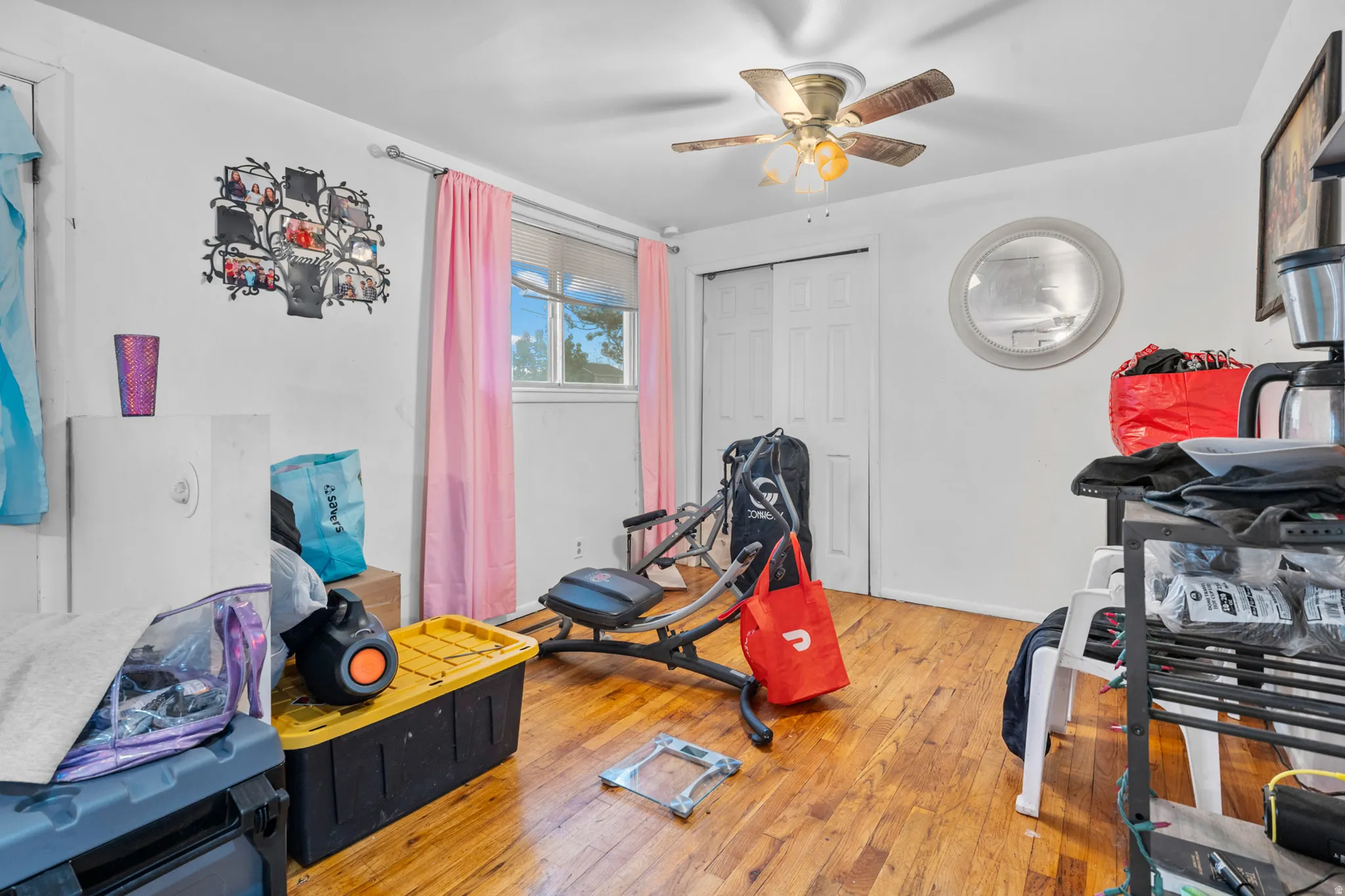 Room featuring wood-finish flooring, a ceiling fan with integrated lighting, and a window with privacy blinds
