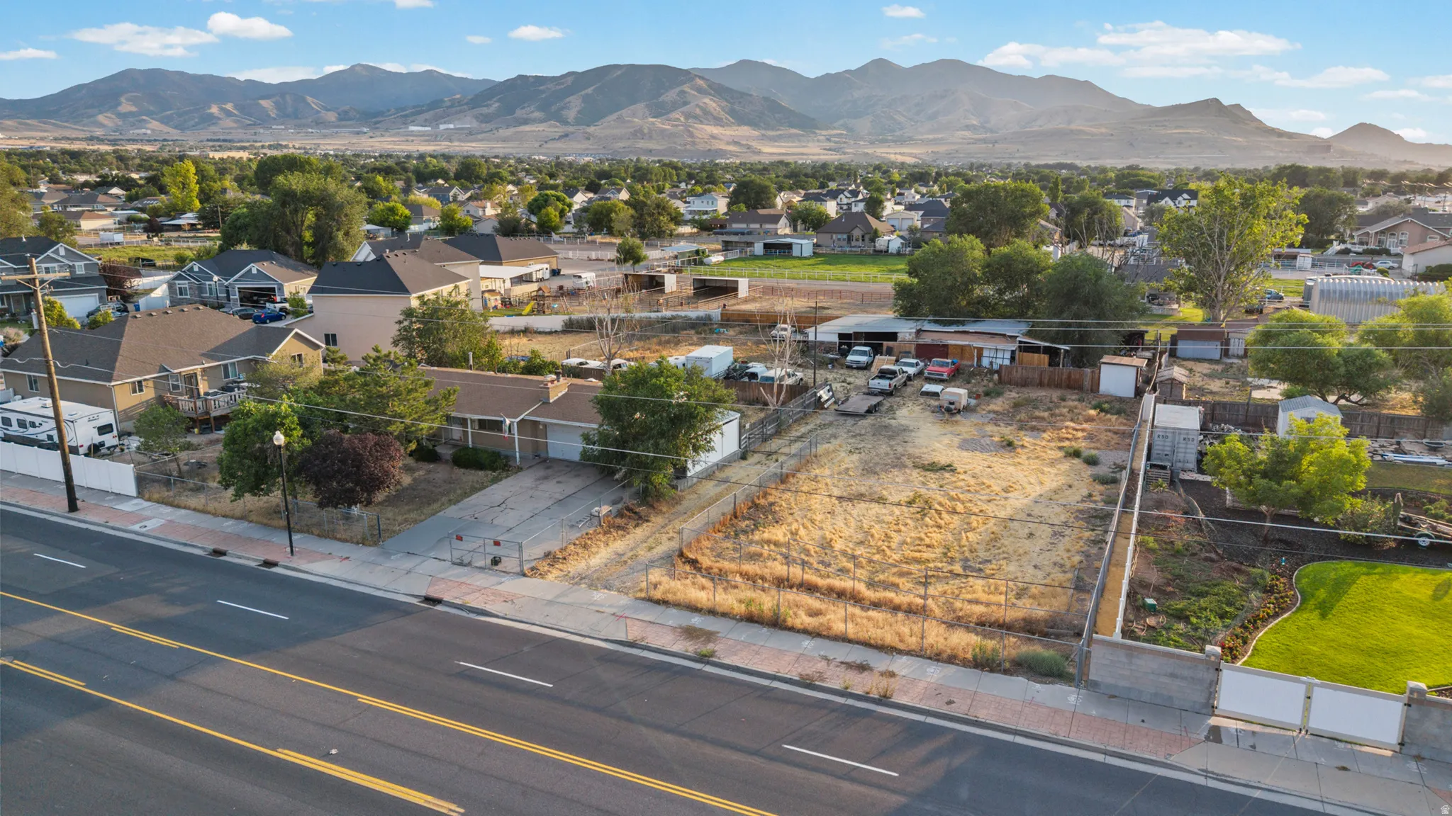 Expansive lot featuring a single-story residence with an attached garage, paved driveway, and mature landscaping