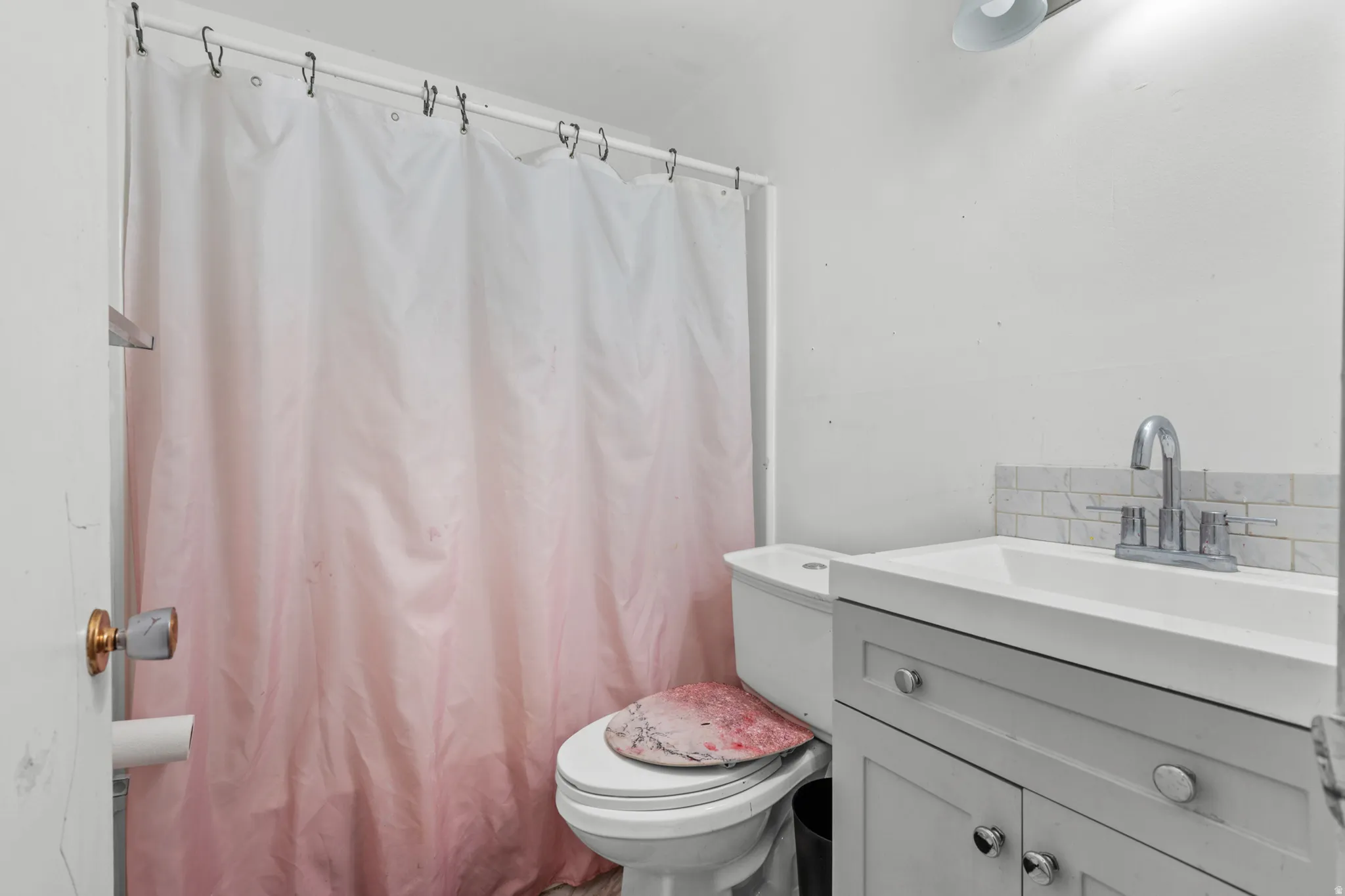 Compact bathroom featuring a white vanity with integrated sink, coordinating subway tile backsplash, and a modern chrome faucet