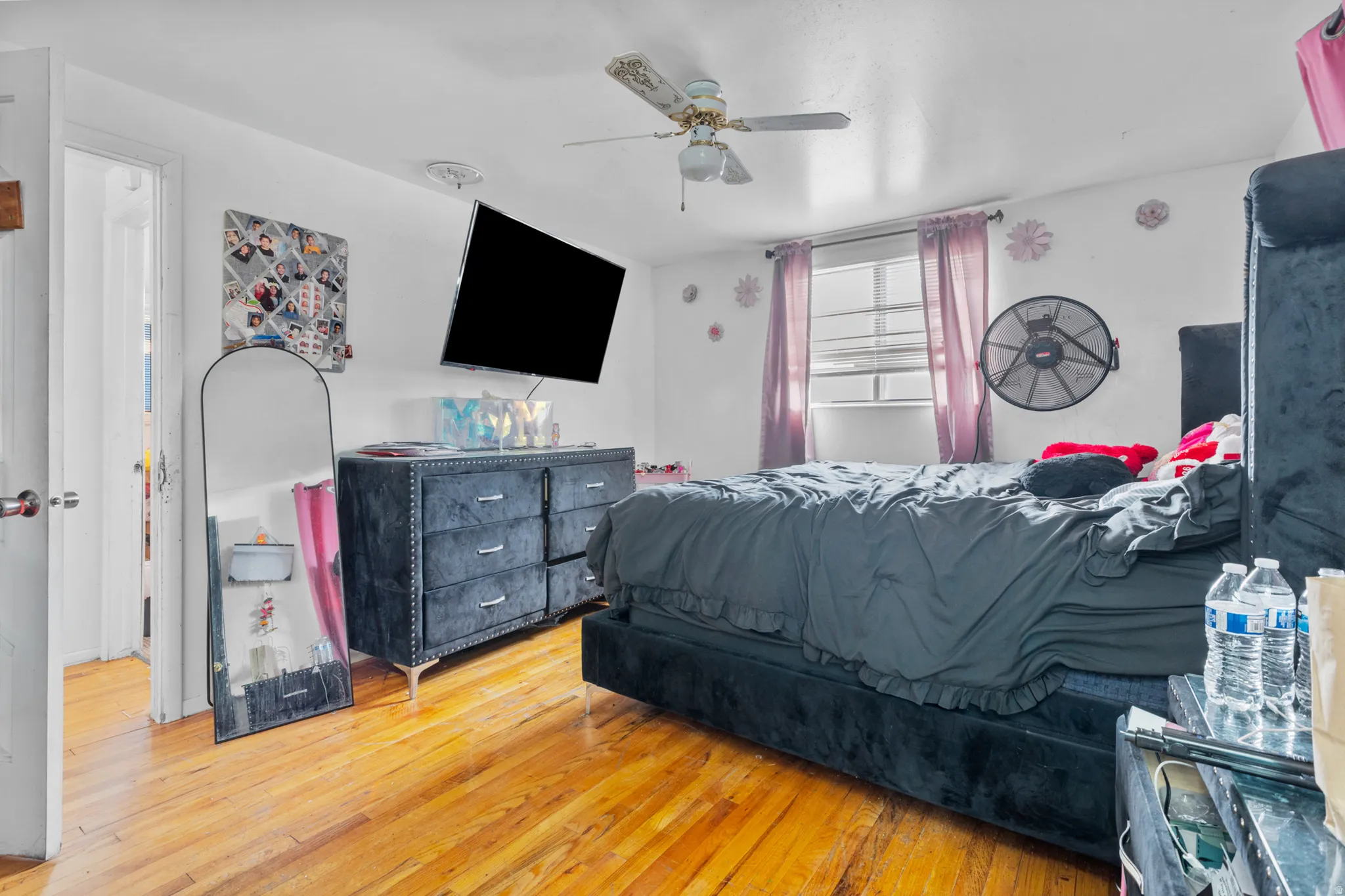Hardwood-finish flooring throughout, featuring a ceiling fan and a window with blinds