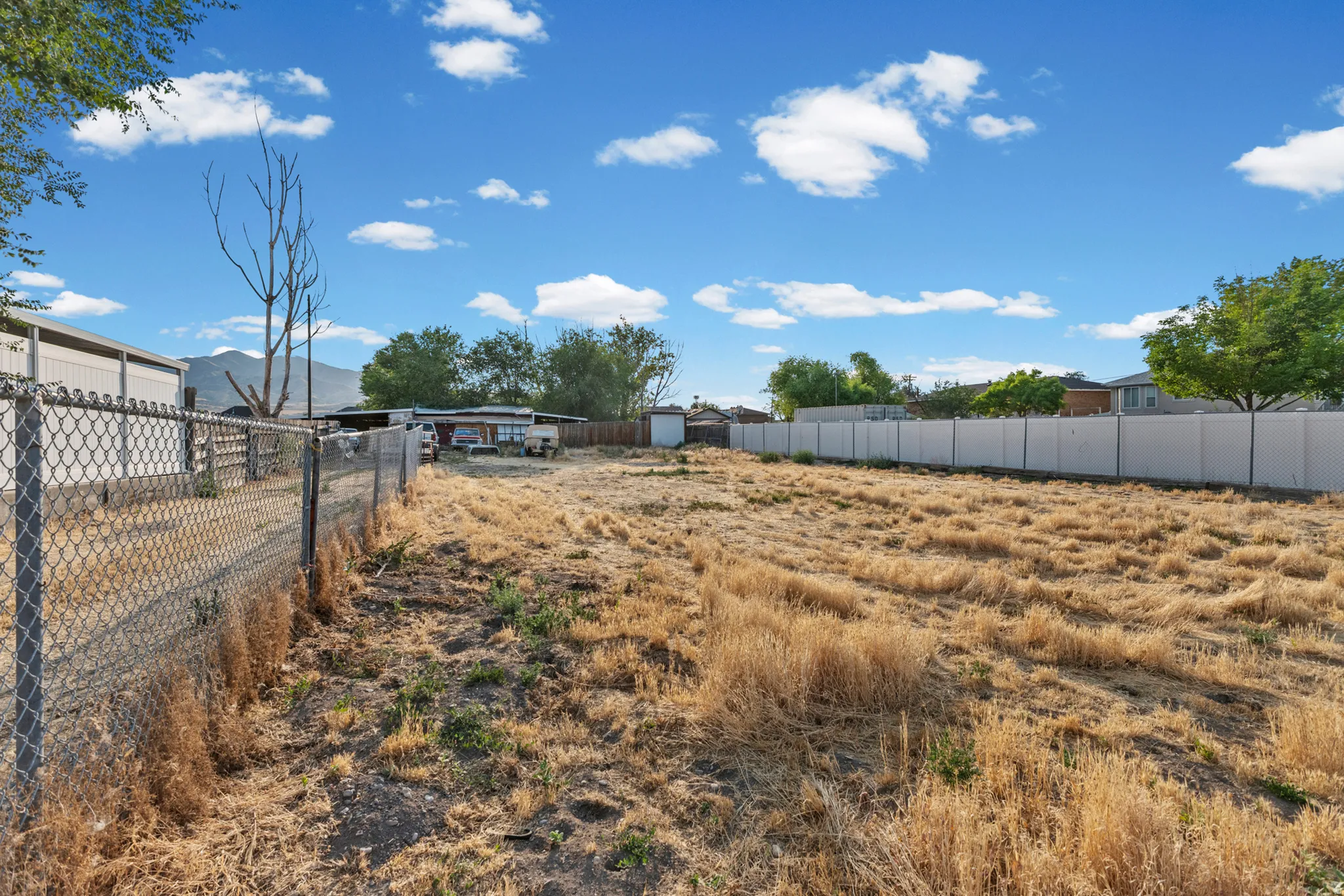 Spacious lot featuring perimeter fencing, an expansive open area, and distant mountain scenery