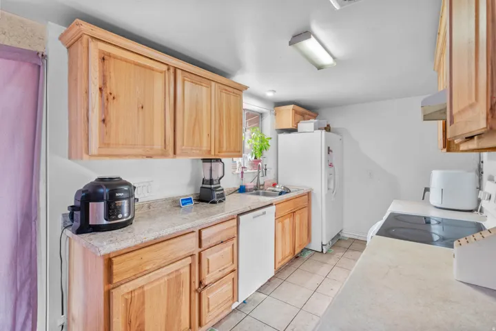 Kitchen featuring natural wood-finish cabinetry, light-toned countertops, and a white dishwasher